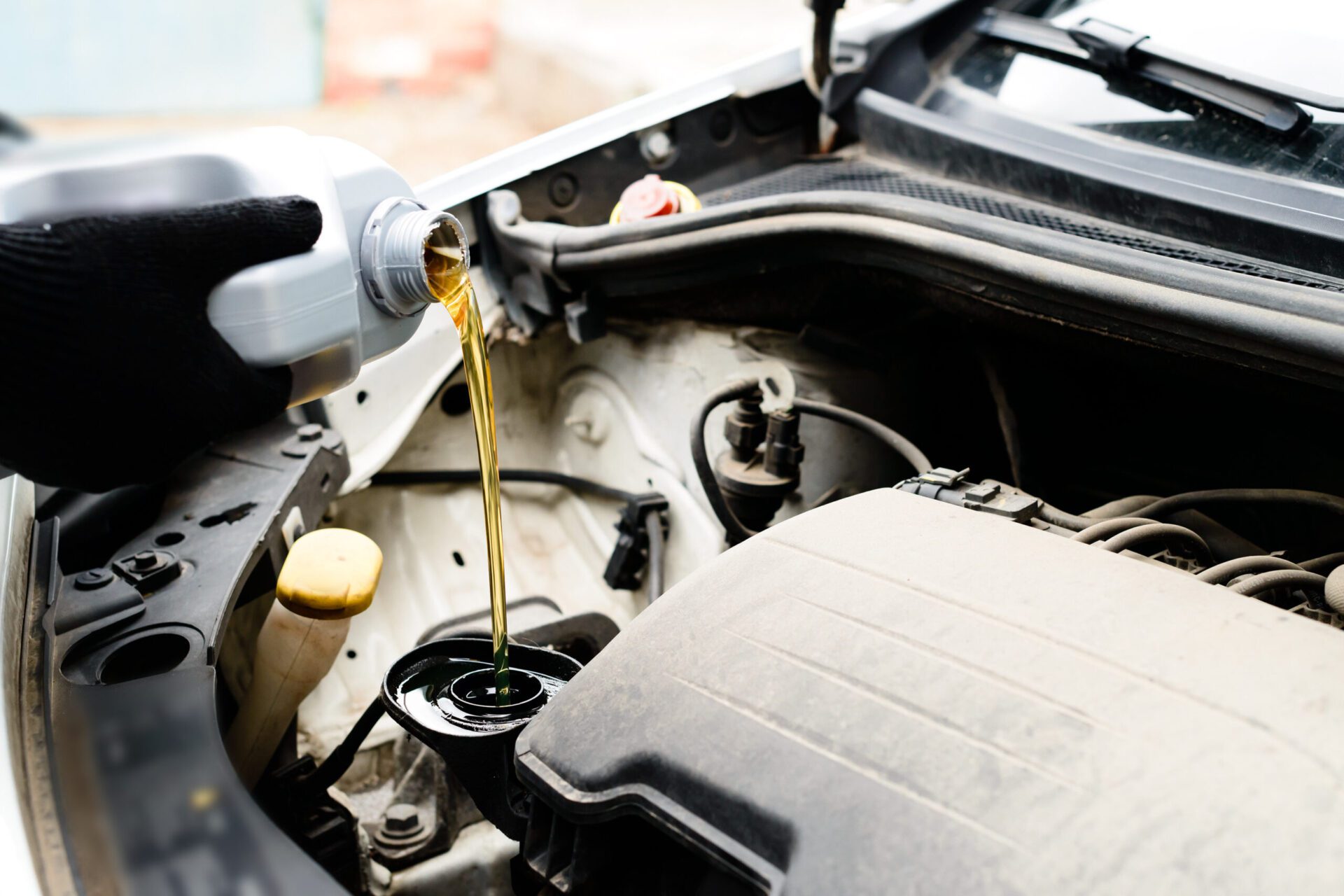 Fresh oil being poured during an oil change to car engine, close-up