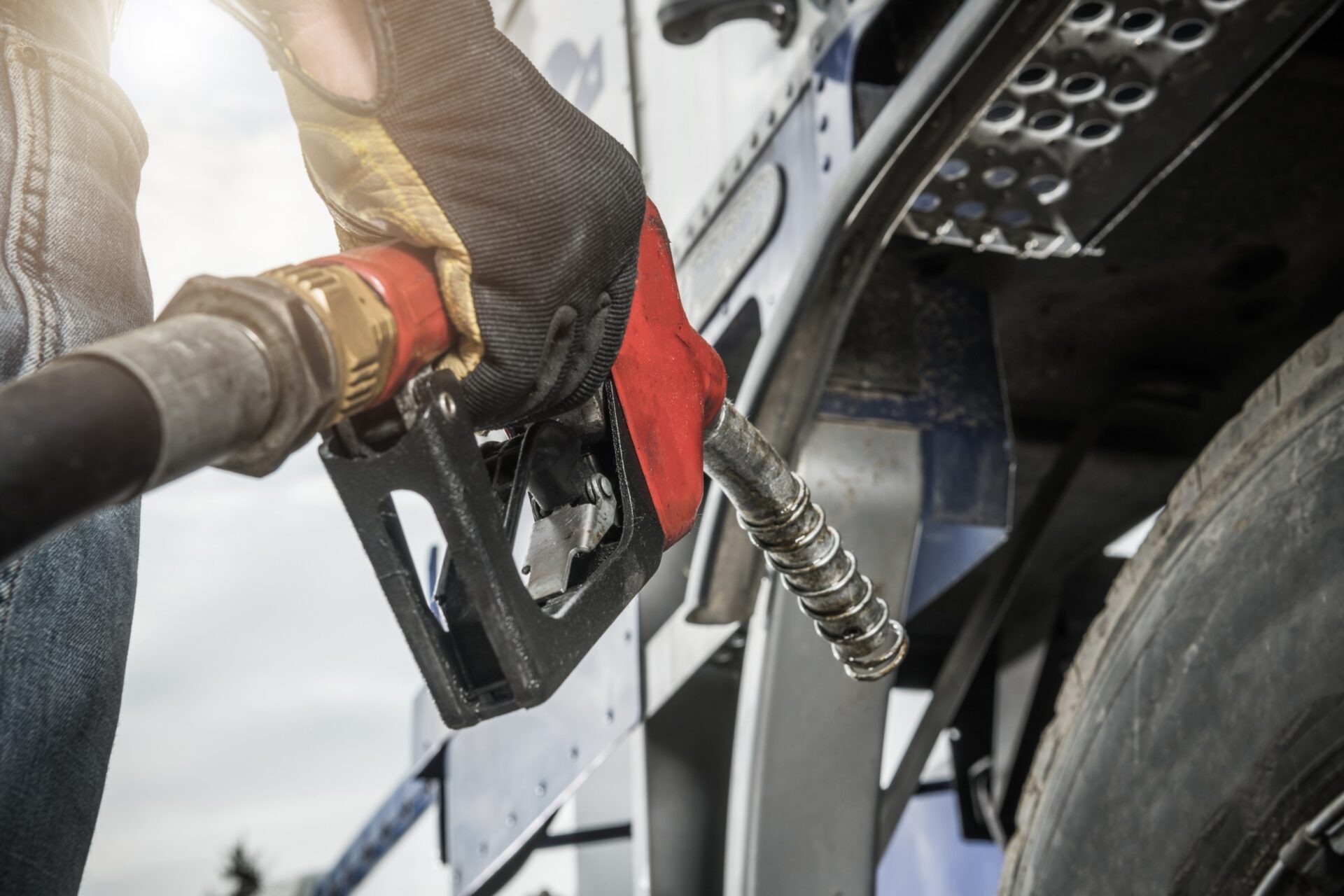 Truck Driver Wearing Safety Gloves Holding Fuel Pump Nozzle in His Hand and Performing Vehicle Refueling