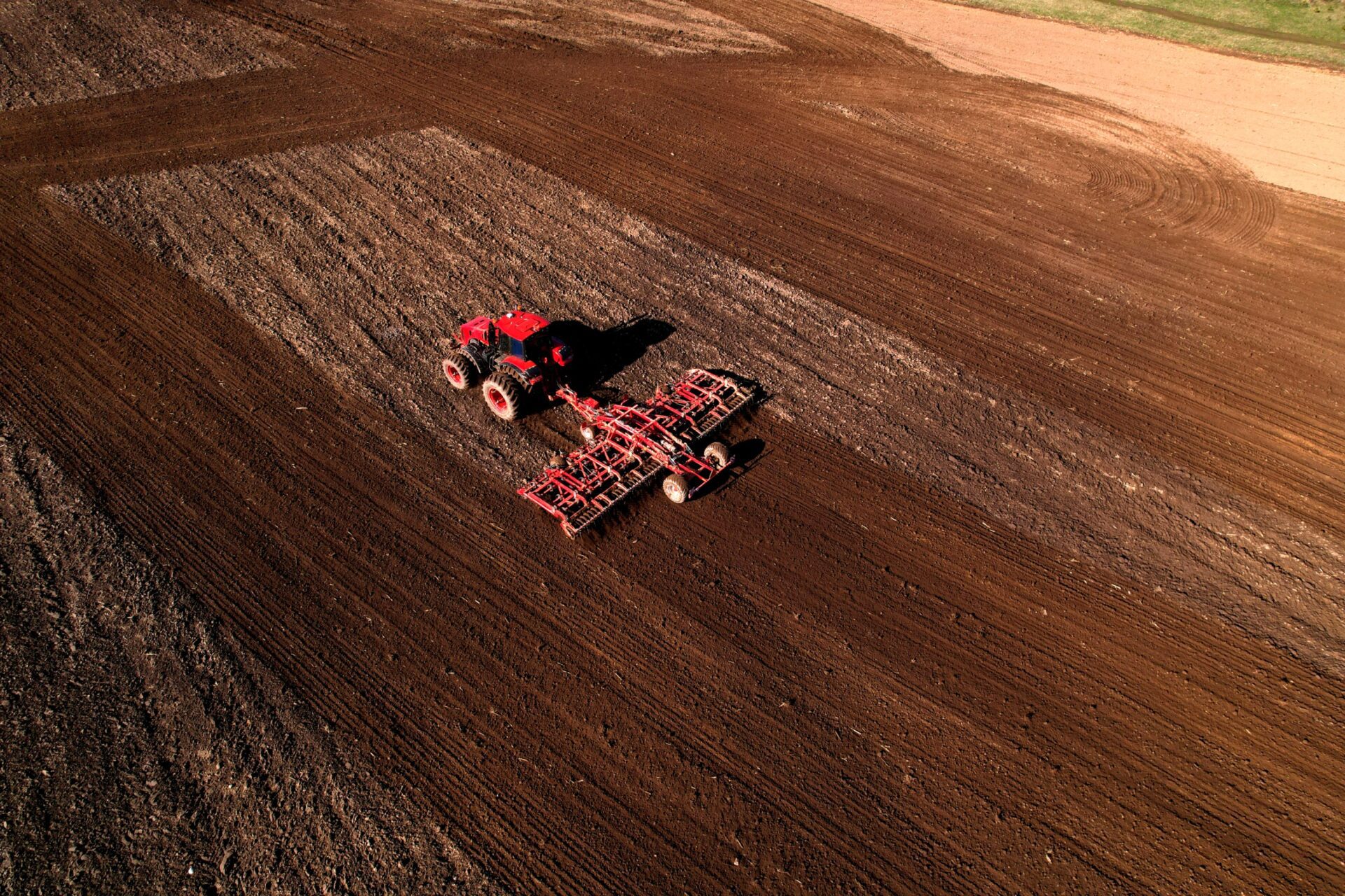 Tractor disk harrow on ploughing a soil. Sowing seed on plowed field on sunset.